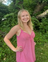 Lydia smiles in front of greenery